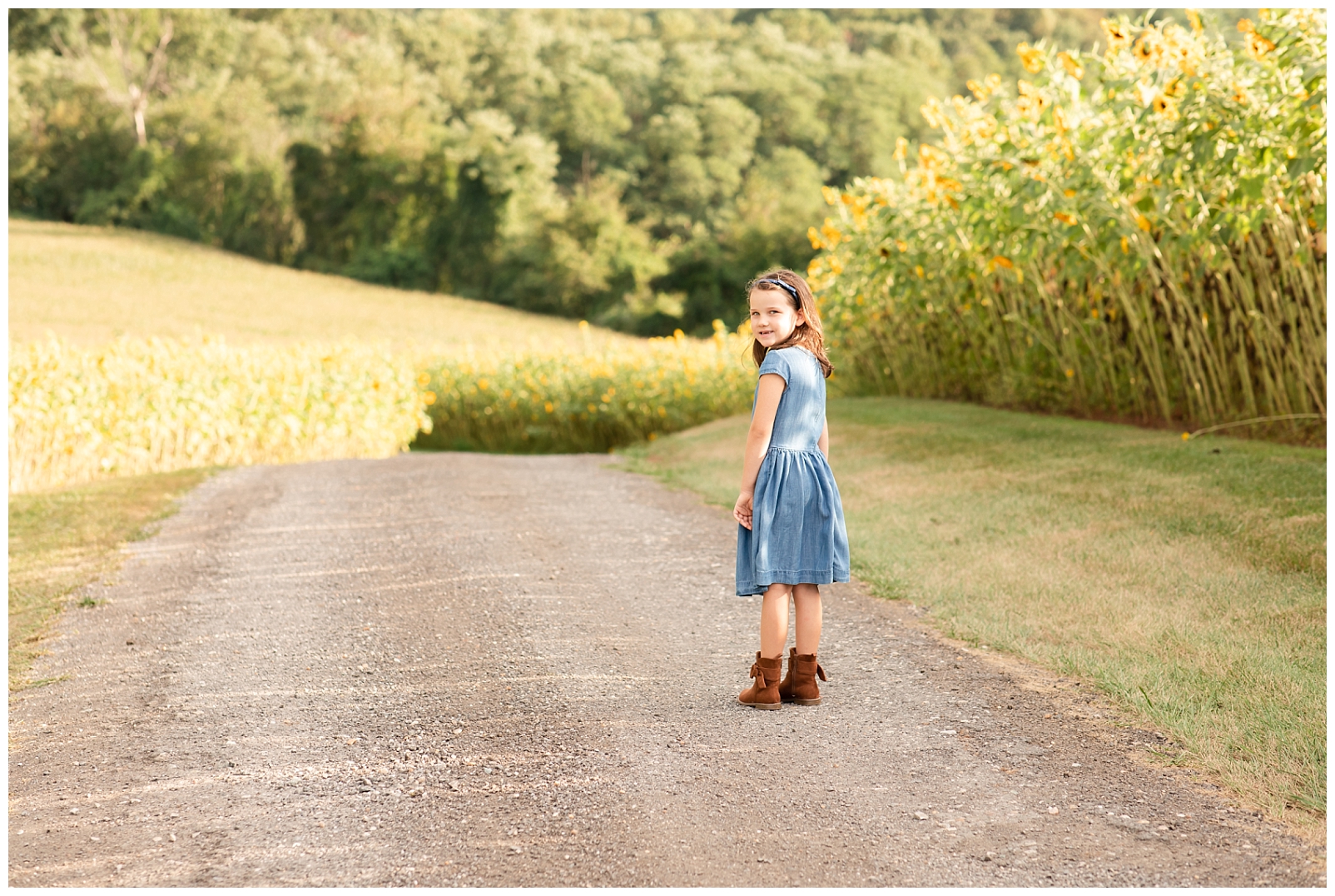 girl standing on road in sunflower field