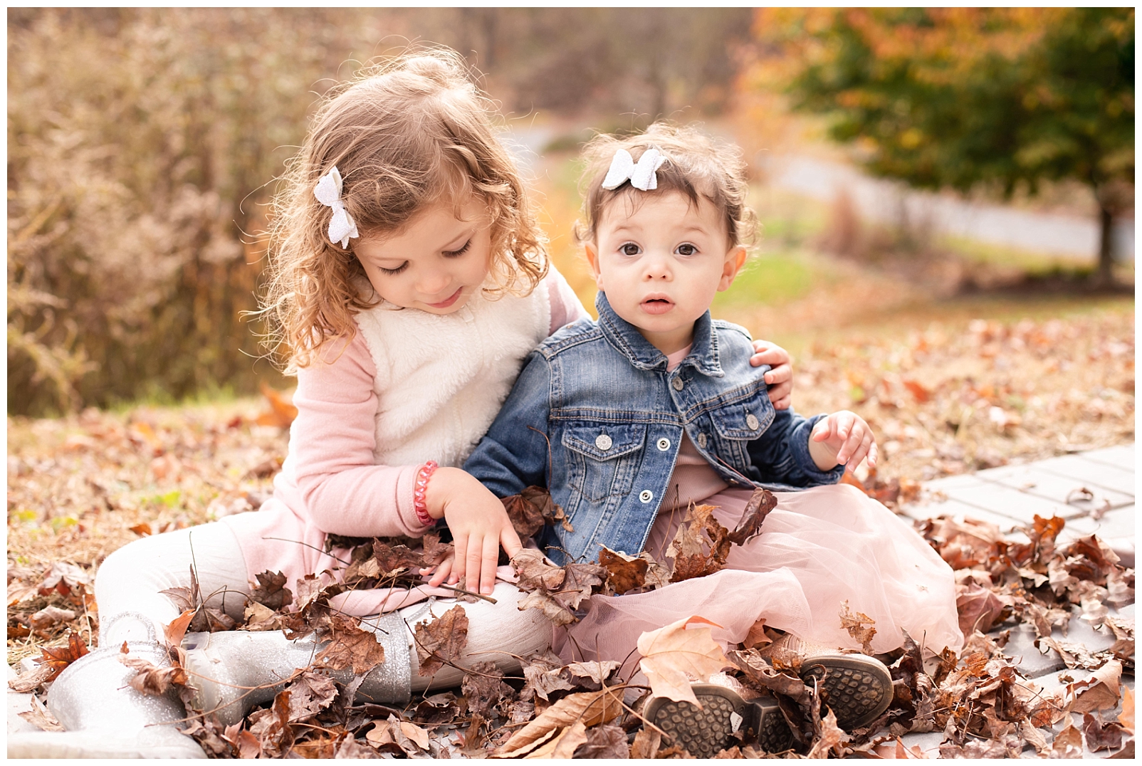 sisters playing in fall leaves