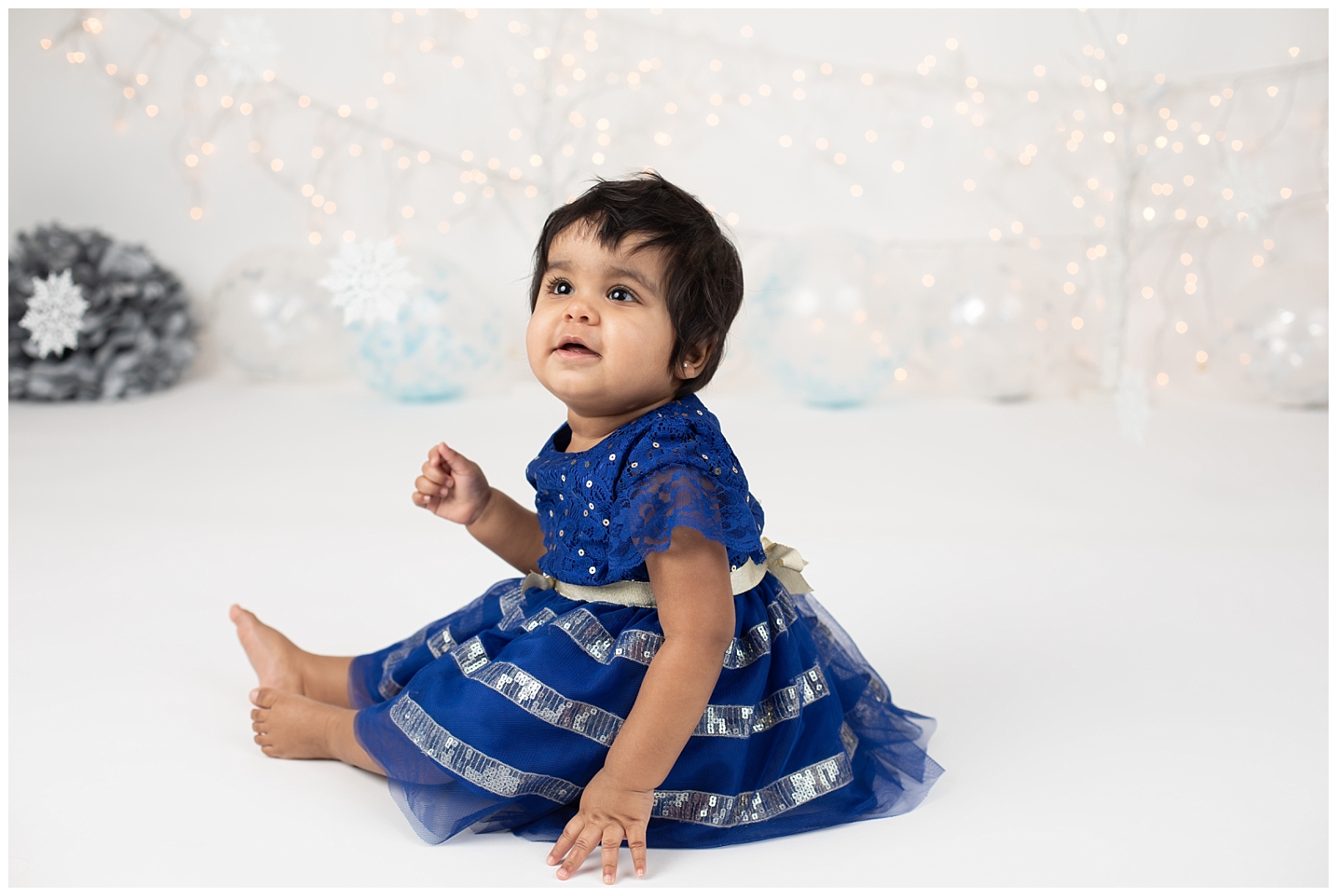 Baby wearing blue dress with snowflakes background