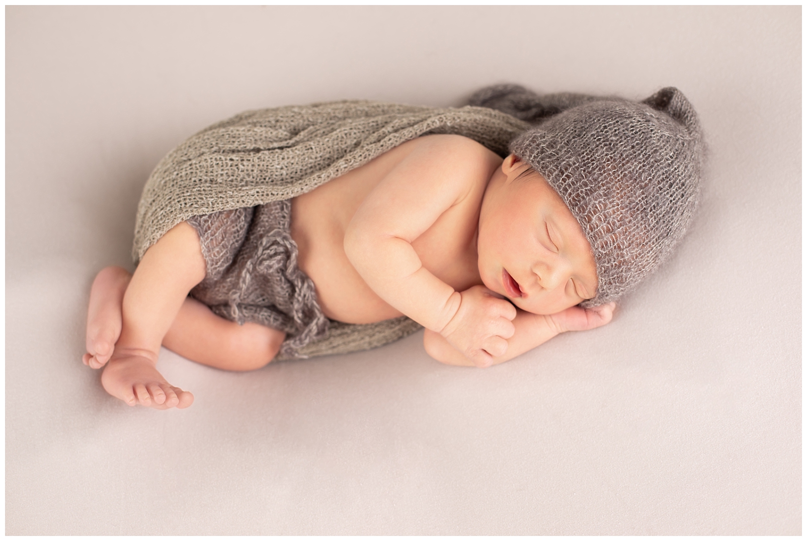 newborn in side lying pose with hat