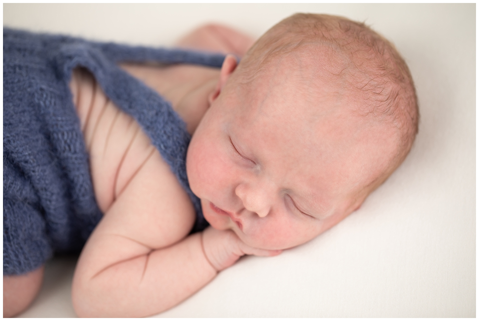 newborn boy in blue overalls