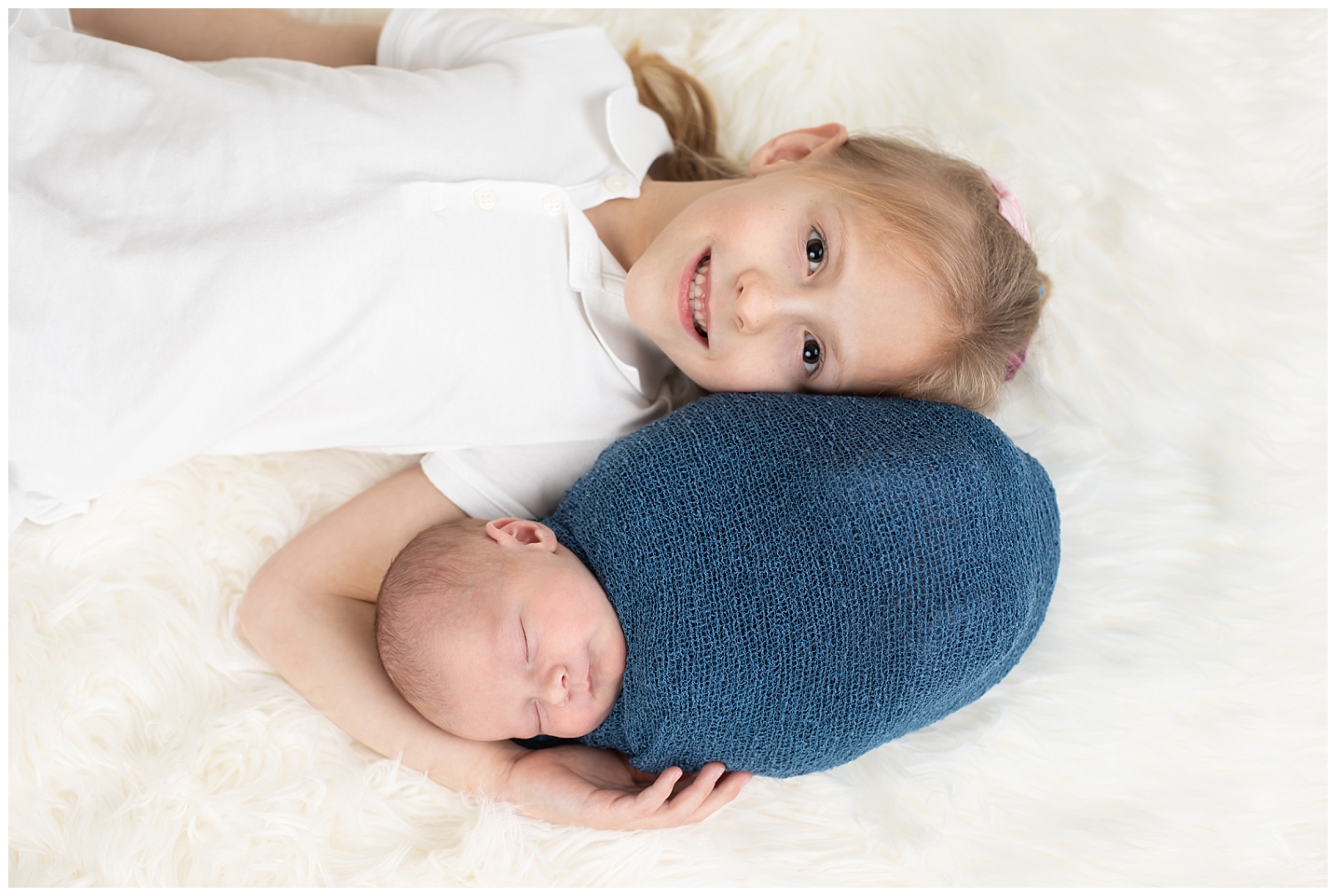 newborn boy in a blue wrap with big sister