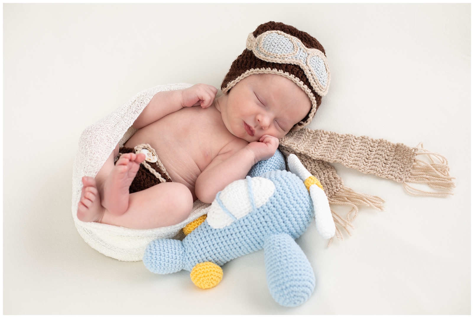 Newborn boy with aviator knit toys
