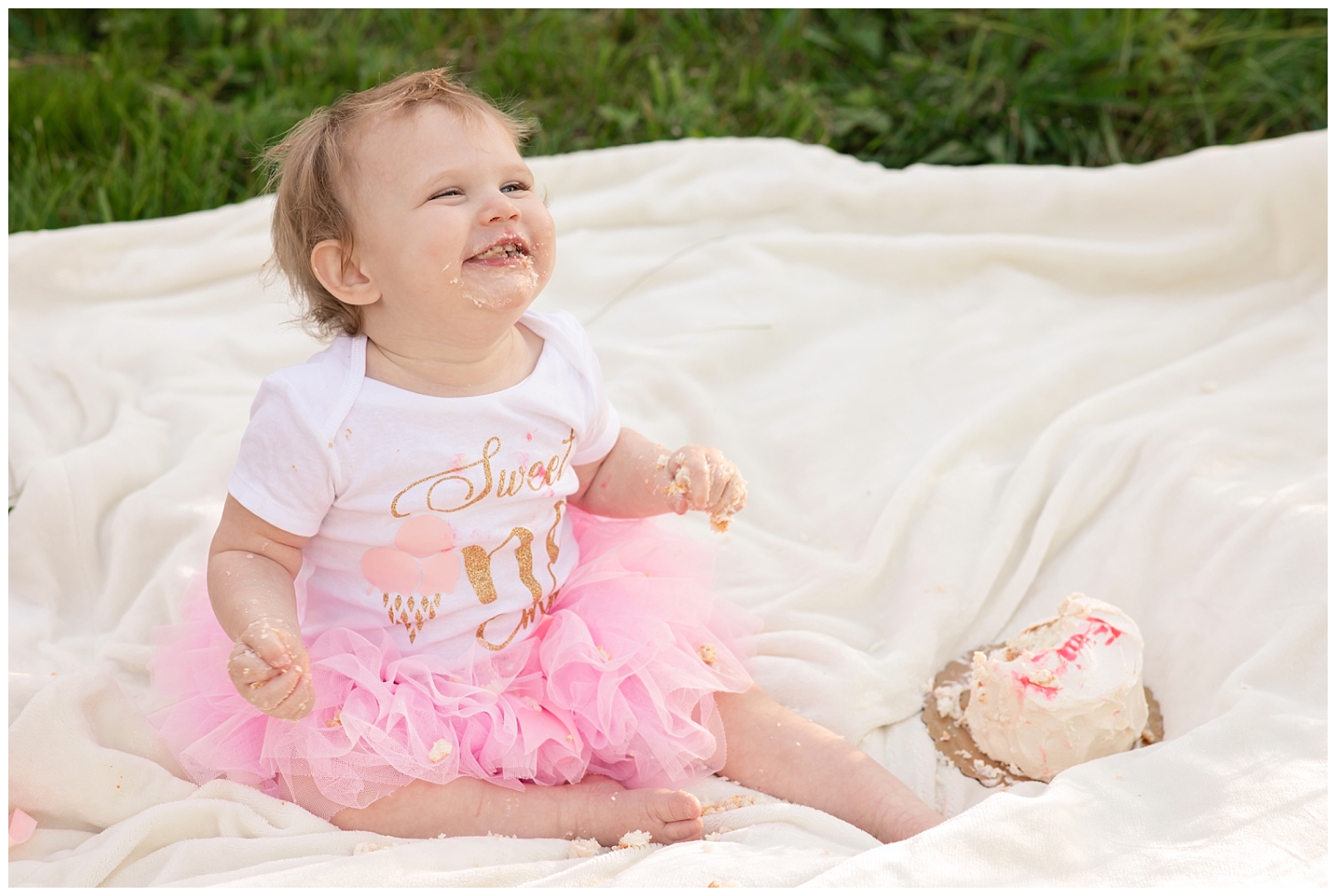 Baby girl wearing a pink tutu dress eating a birthday cake