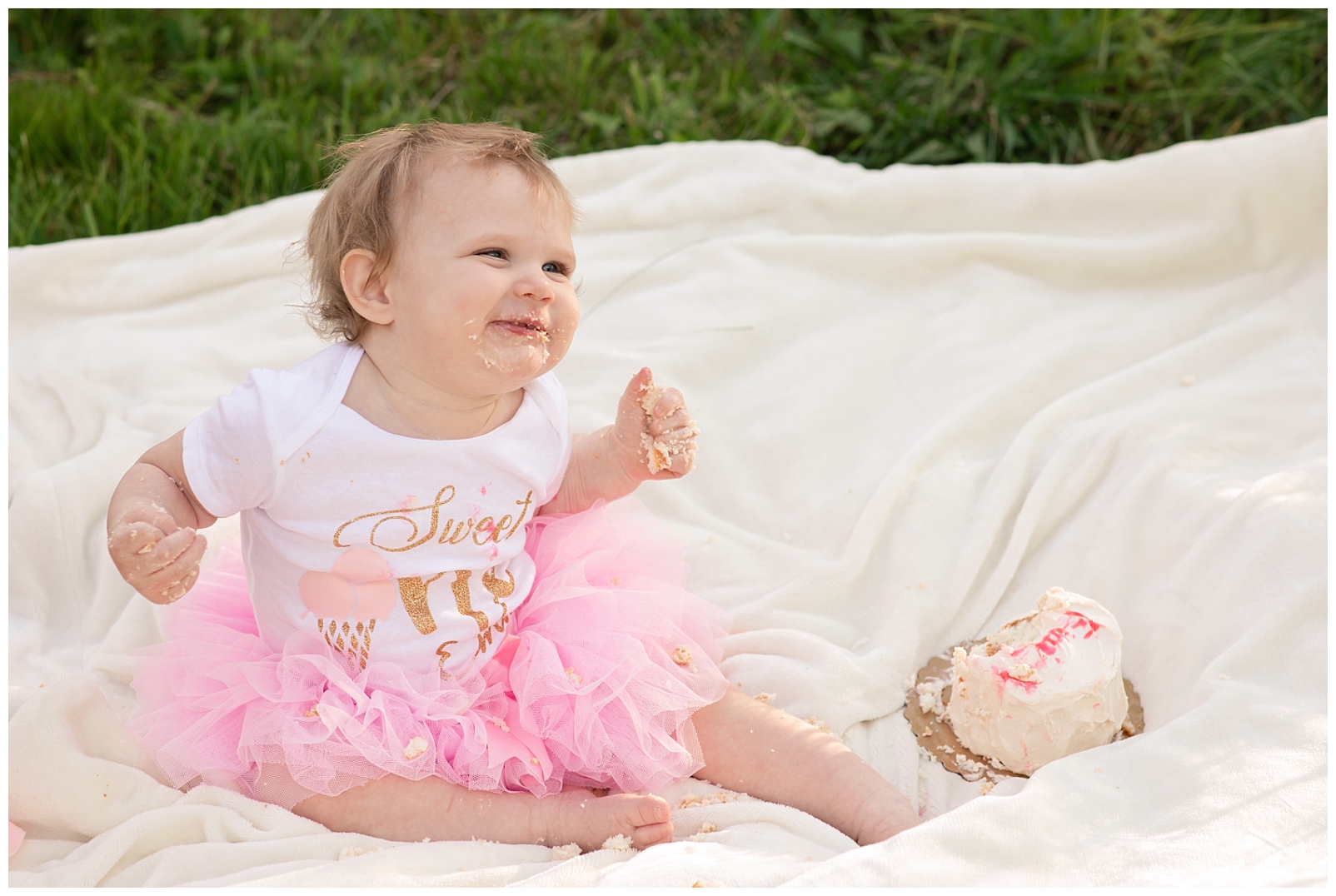Baby girl wearing a pink tutu dress eating a birthday cake