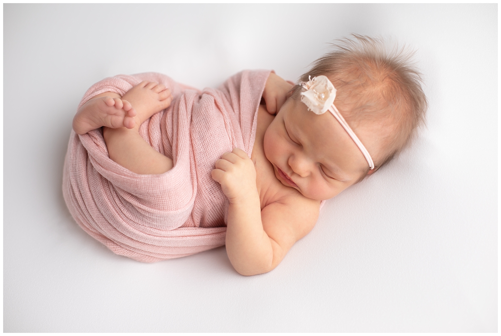 Newborn girl in pink wrap and floral headband