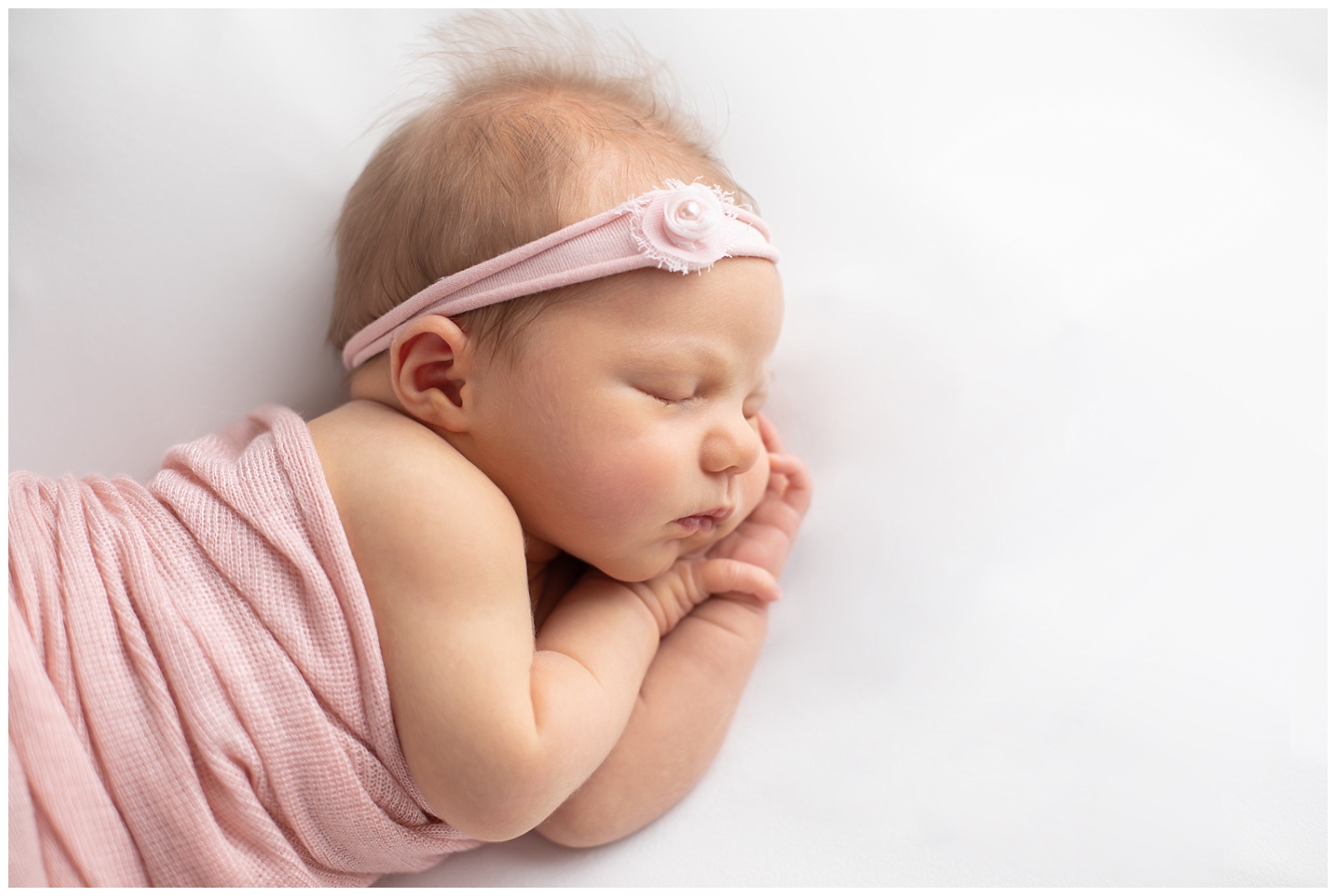 Newborn girl in pink wrap and floral headband