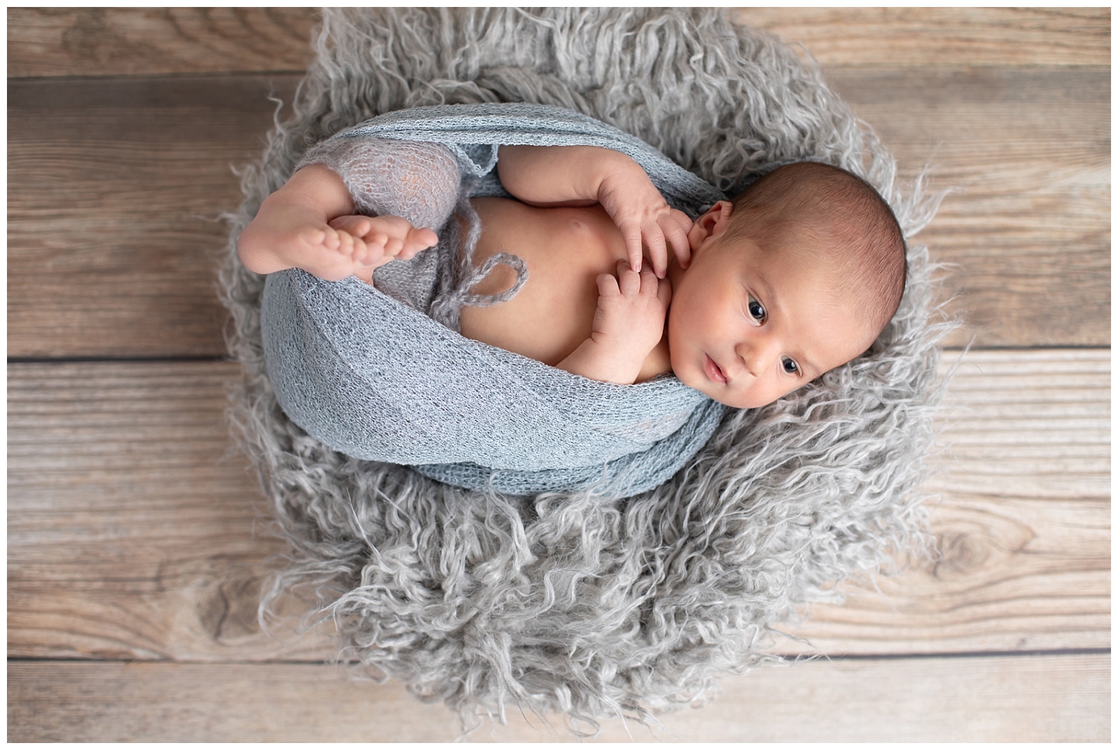 newborn boy wrapped in gray in a basket