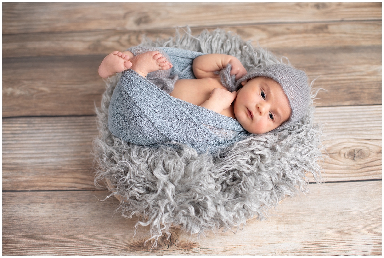 newborn boy wrapped in gray in a basket