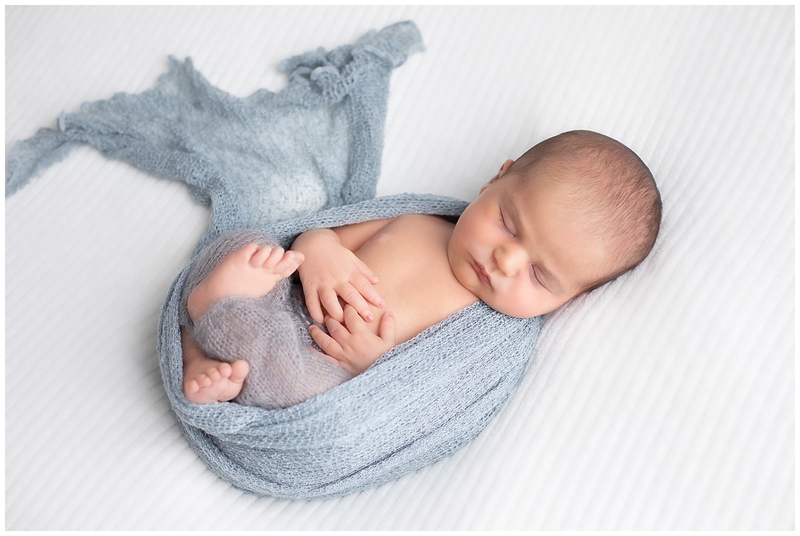 newborn wrapped in gray on back