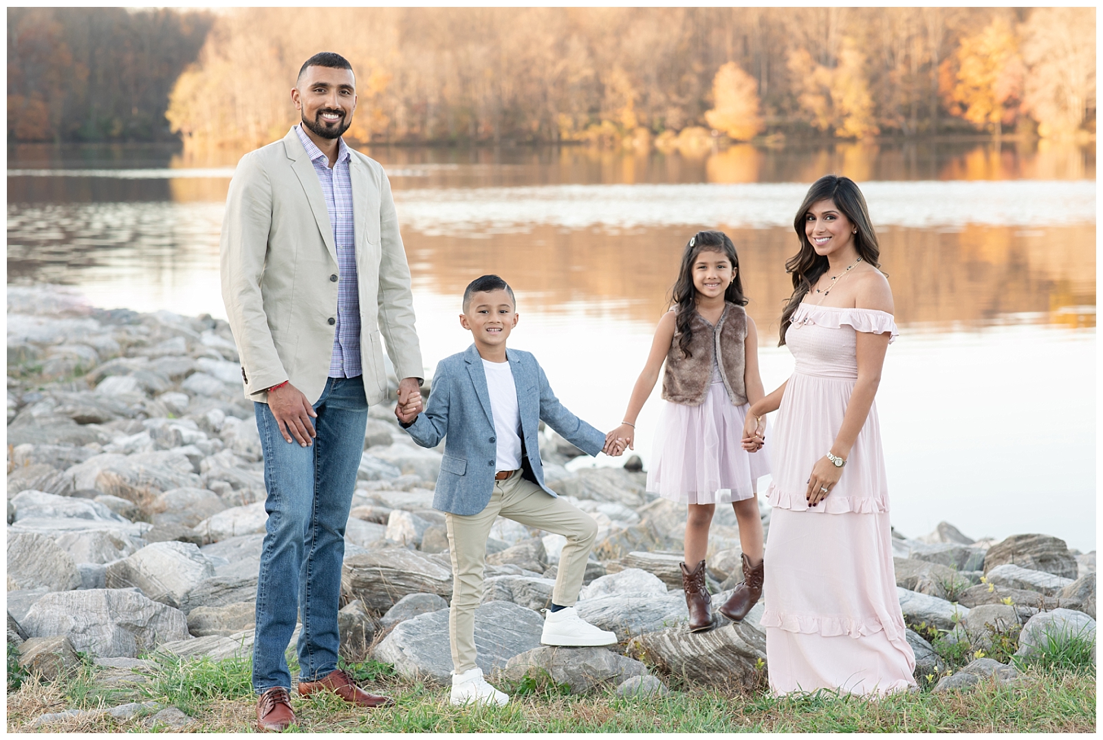 family of four standing near rocks and a lake