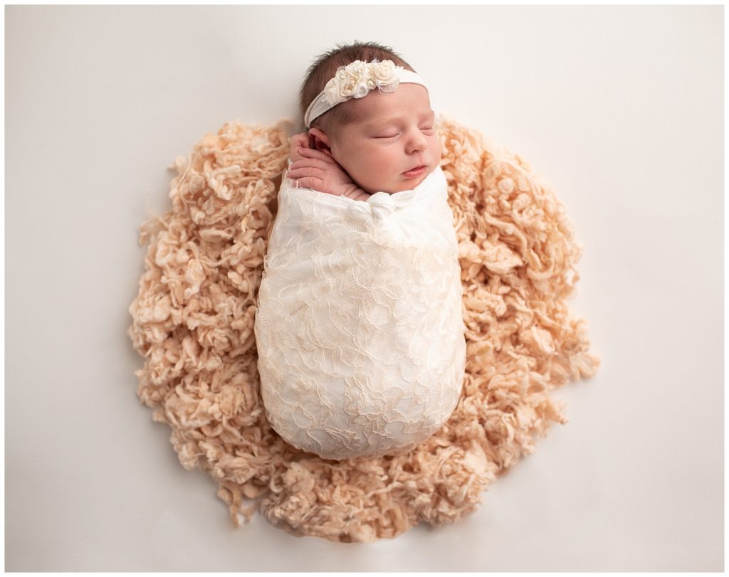Newborn in a lace wrap on peach wool