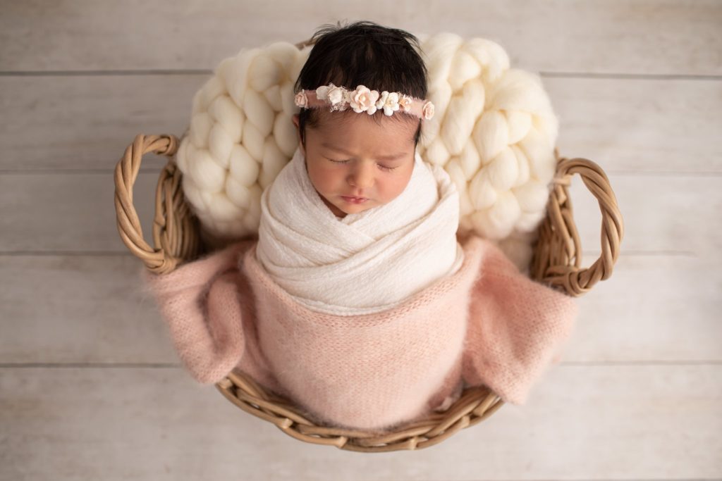 Isla Headband worn by newborn wrapped in a basket with a woven blanket