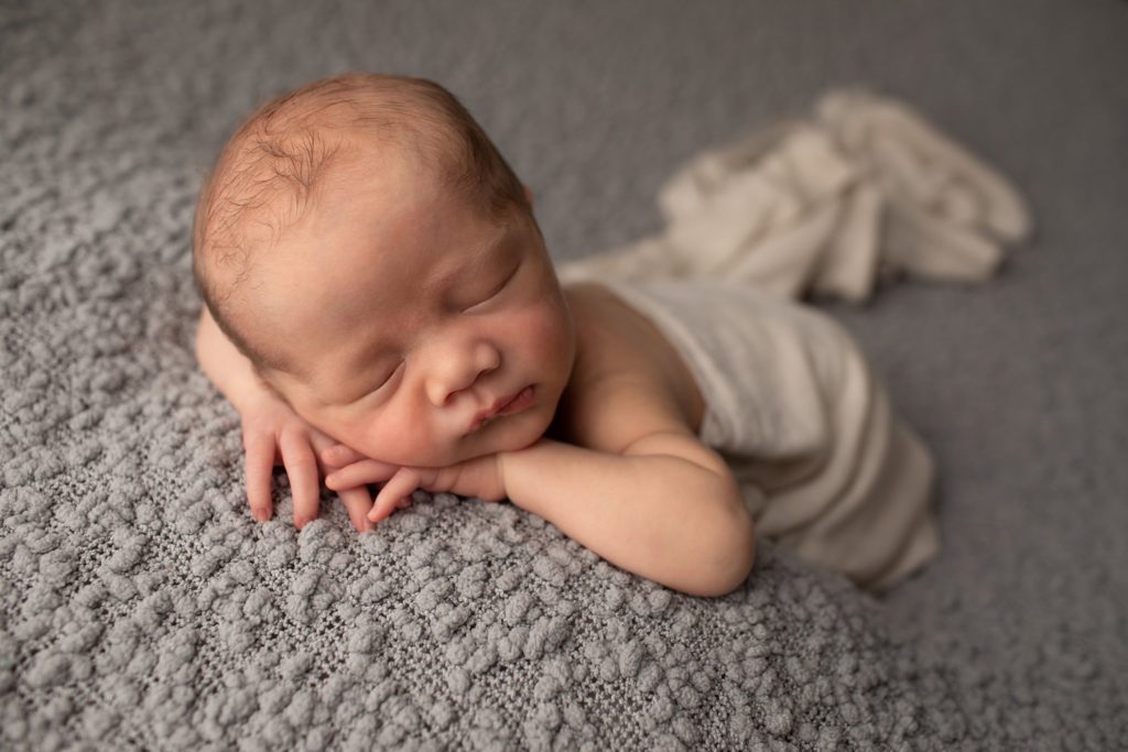 Newborn boy on gray blanket