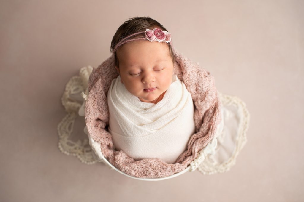 newborn girl wrapped in a bucket with Penelope headband
