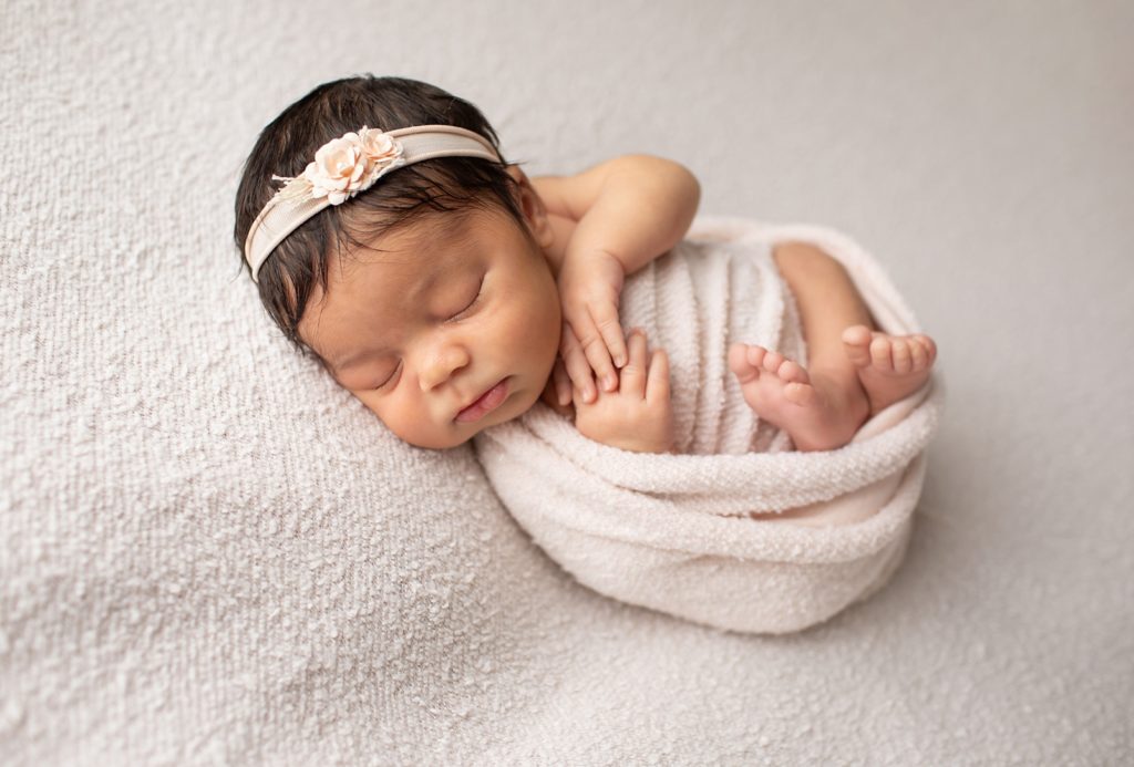 newborn girl wrapped in pale pink fabric