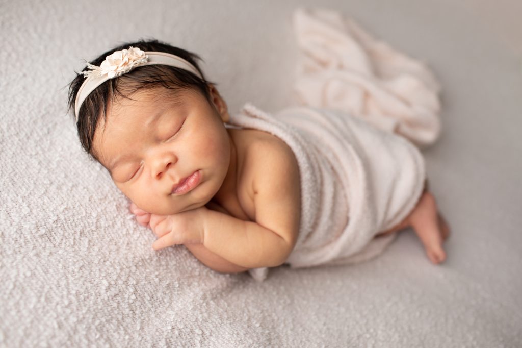 newborn girl wrapped in pale pink fabric