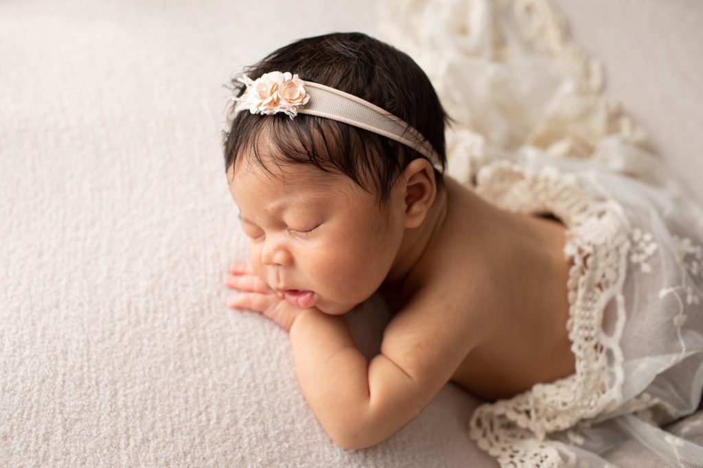 Newborn girl lying on tummy with lace wrap