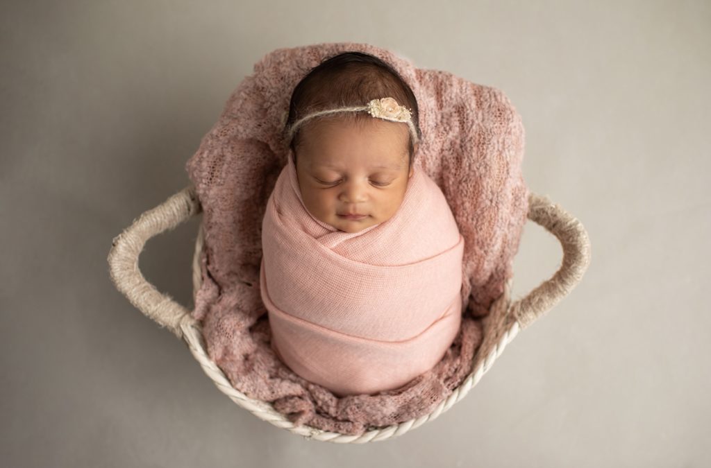 newborn wrapped in blush and in a basket