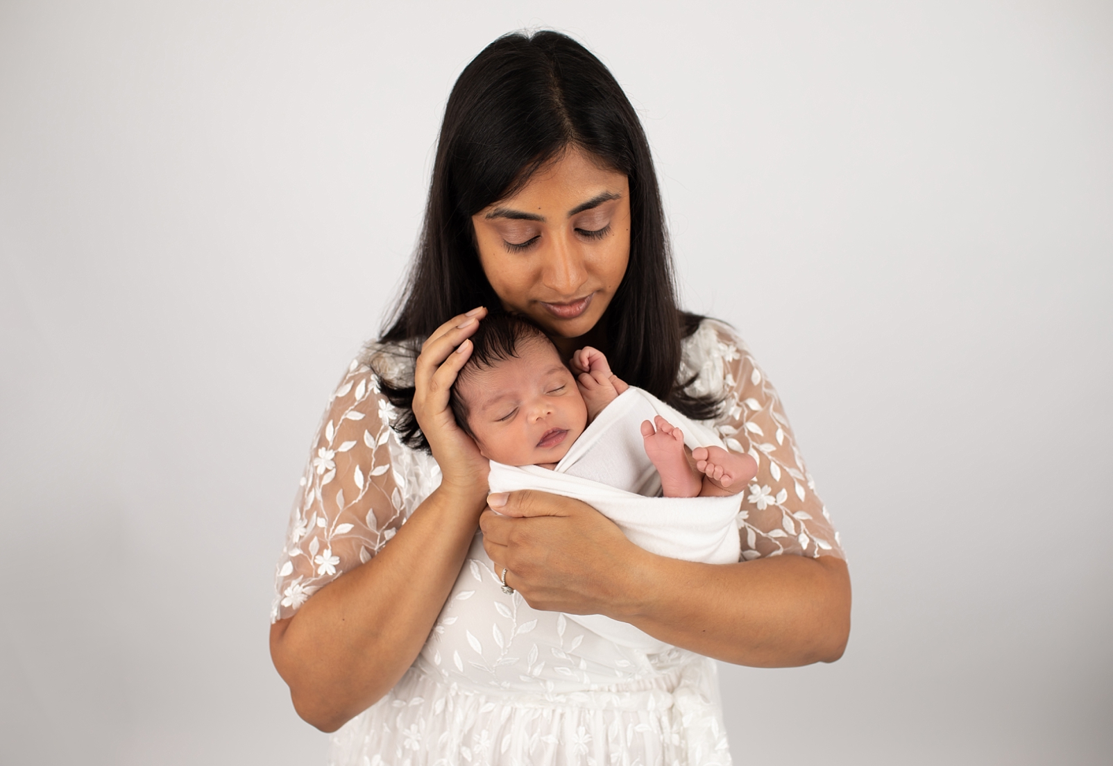 mom with eyes closed holding newborn baby in wrap
