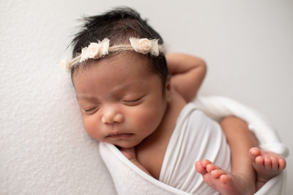 newborn wrapped in white with bow headband