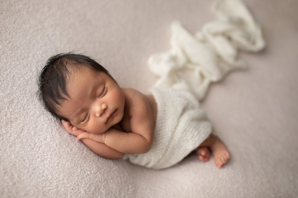 side lying pose of newborn wrapped in white