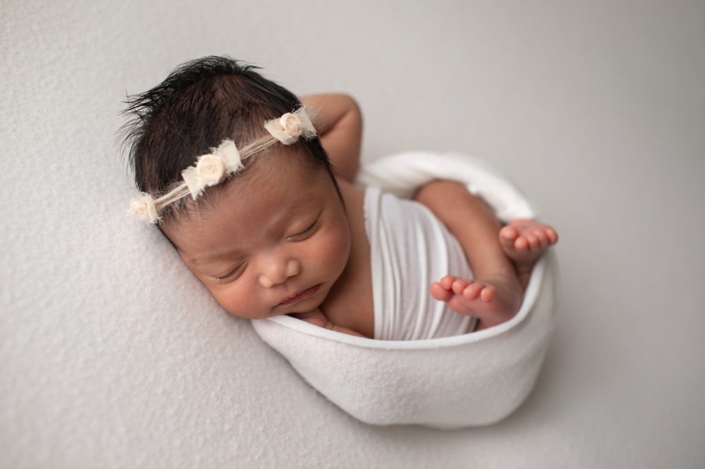 newborn wrapped in white with bow headband