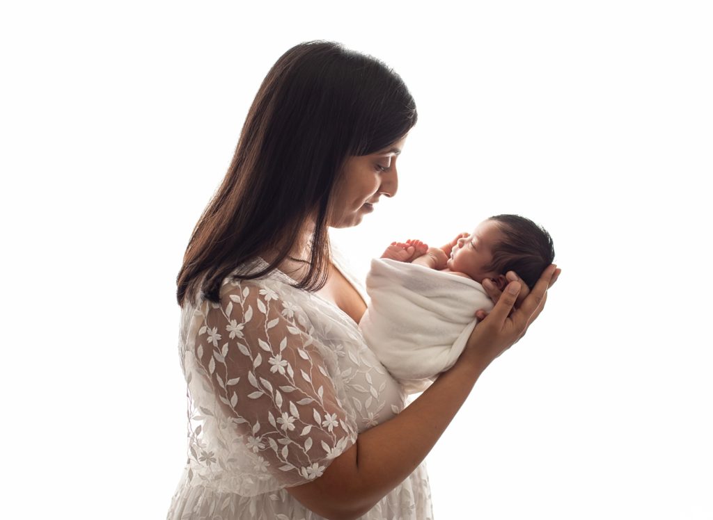 mom in white floral dress looking at newborn with backlighting by Baltimore Newborn Photographer
