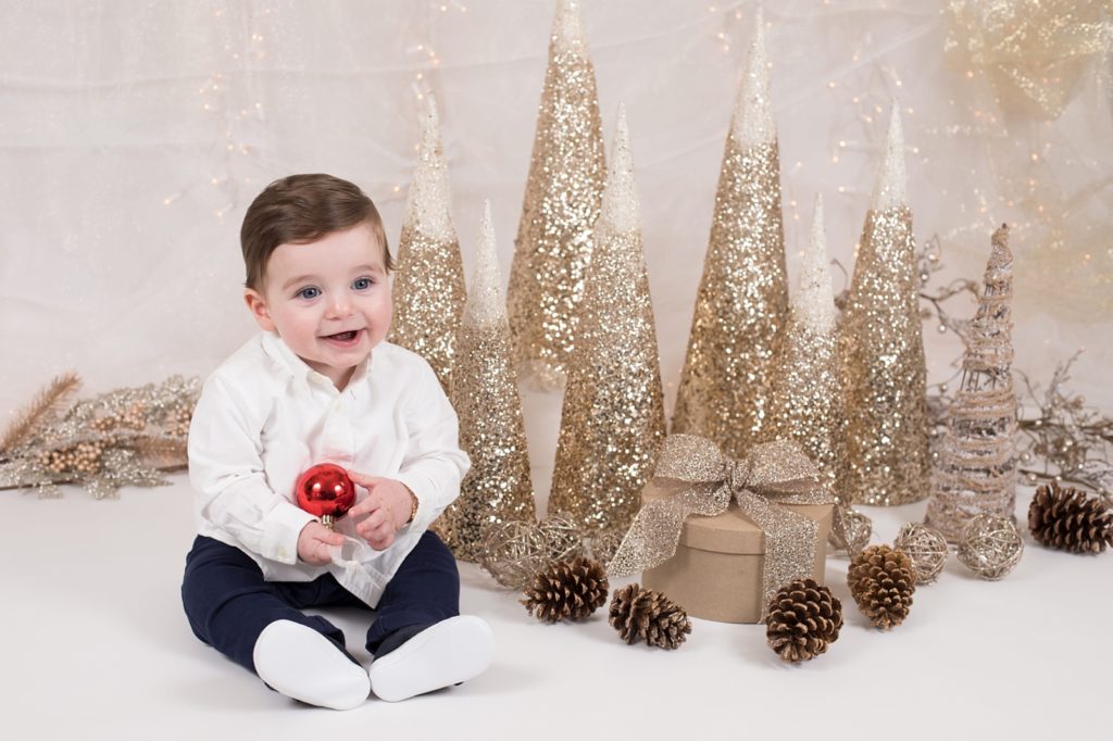 baby boy holding a red ornament