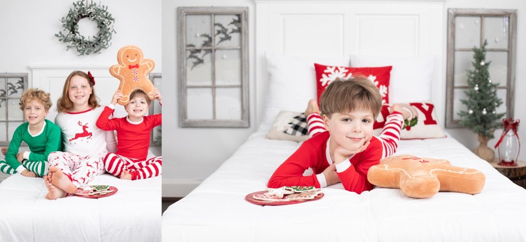 Three children sitting on a white bedspread with a gingerbread man pillow 
