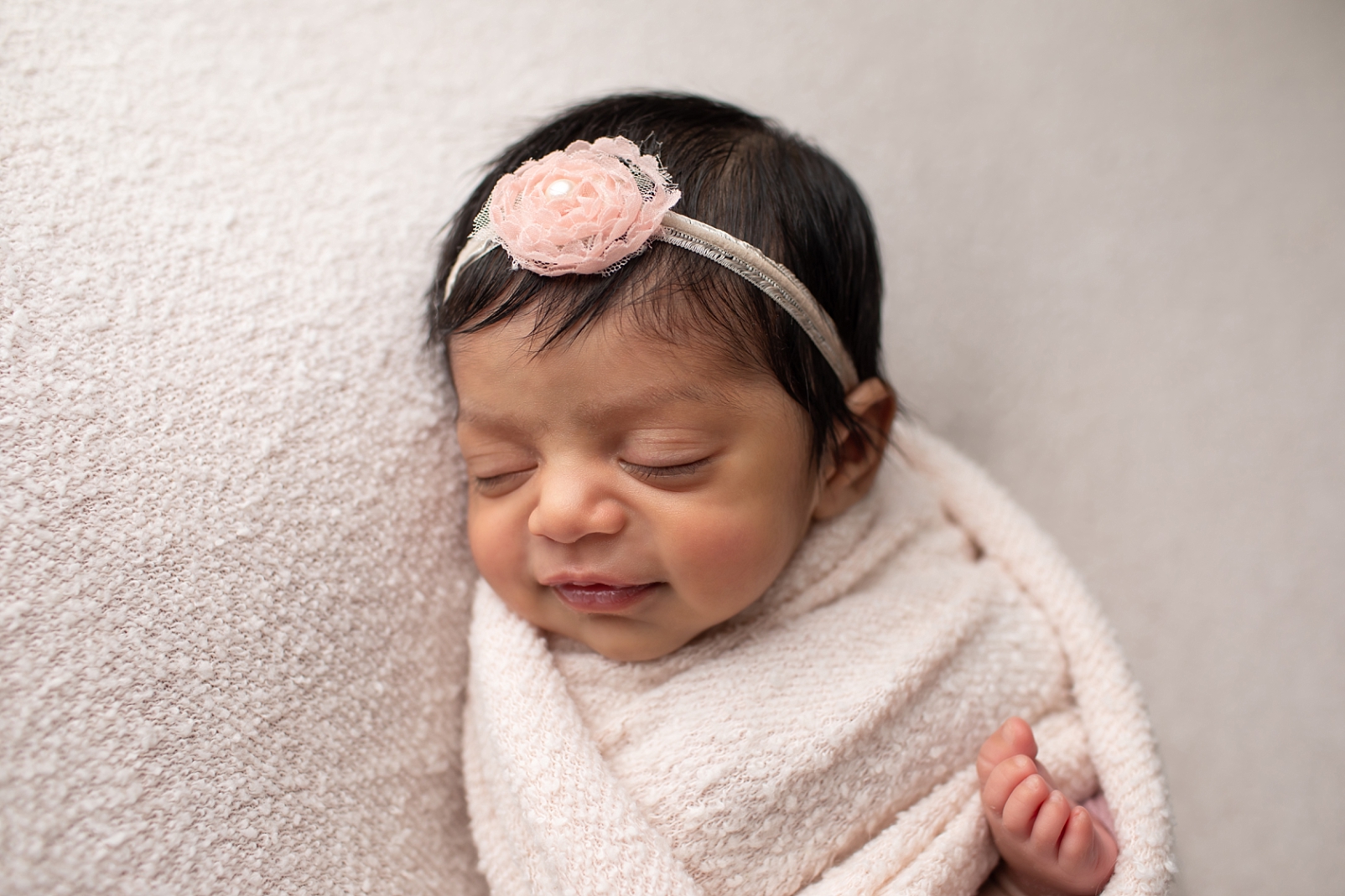 newborn baby smiling with pink flower headband
