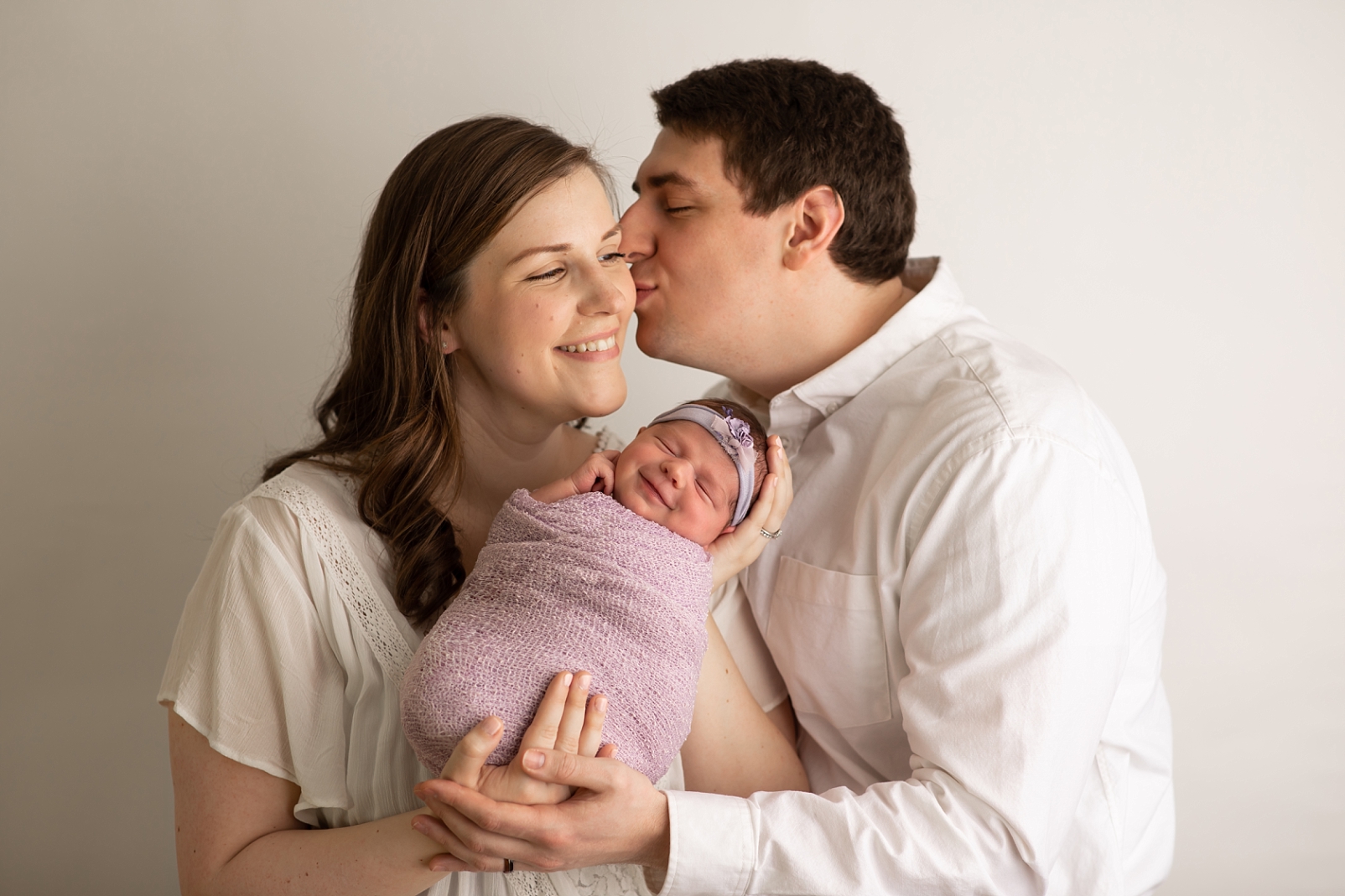 parents holding smiling newborn girl in lavender
