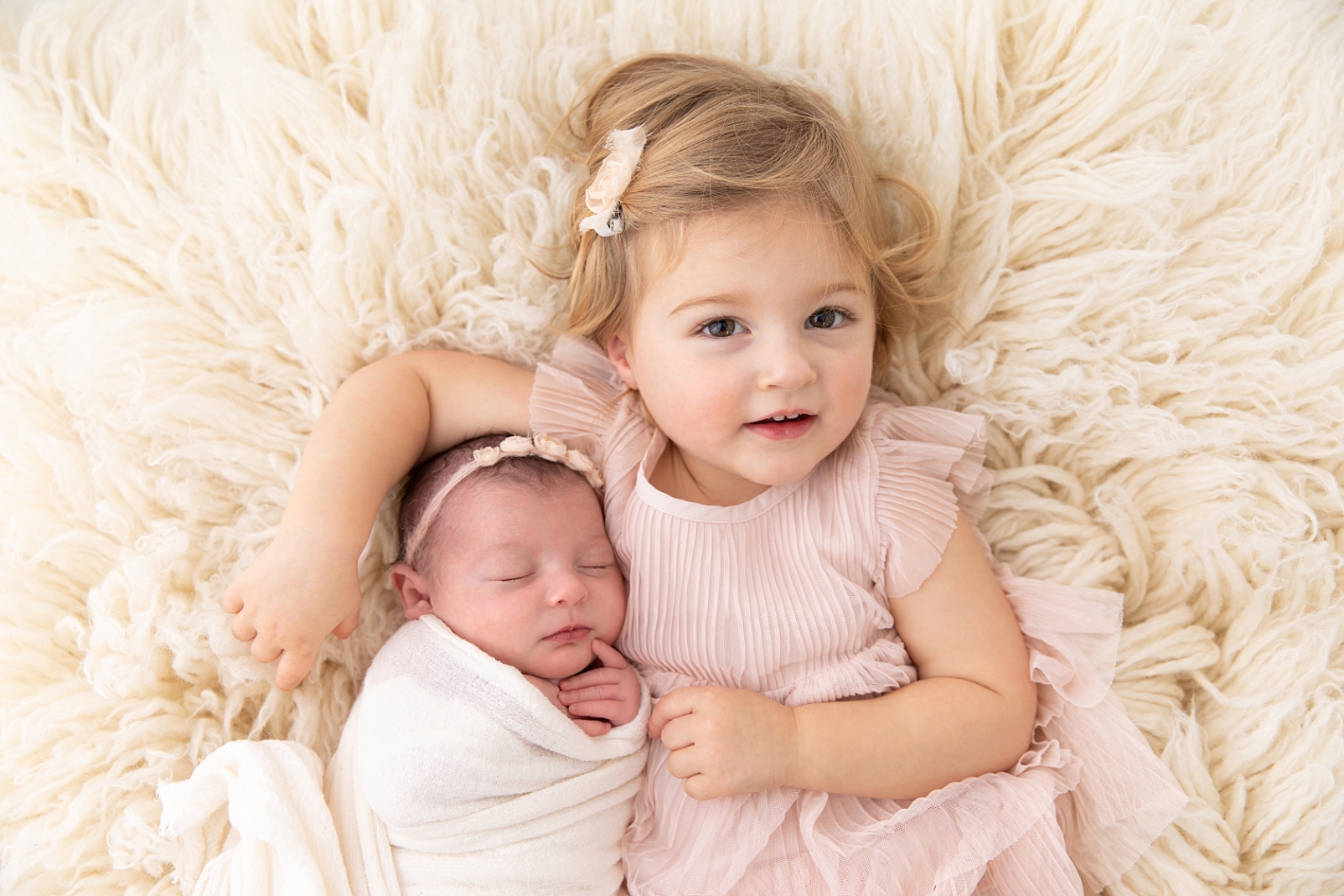 girl on flokati with newborn sister | It's snuggle time