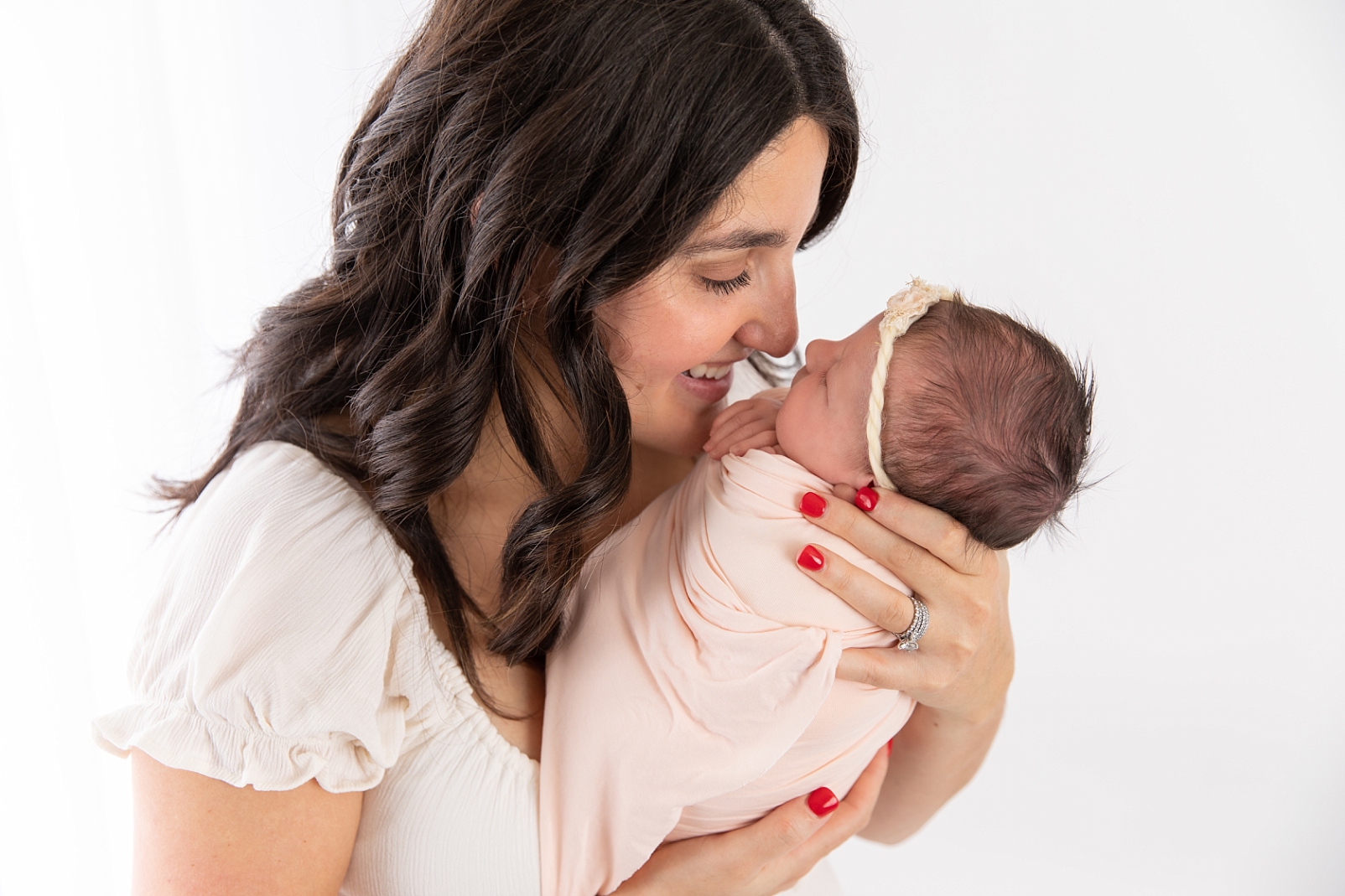 Mom smiling closely at baby girl for newborn photos with Baltimore Newborn Photographer