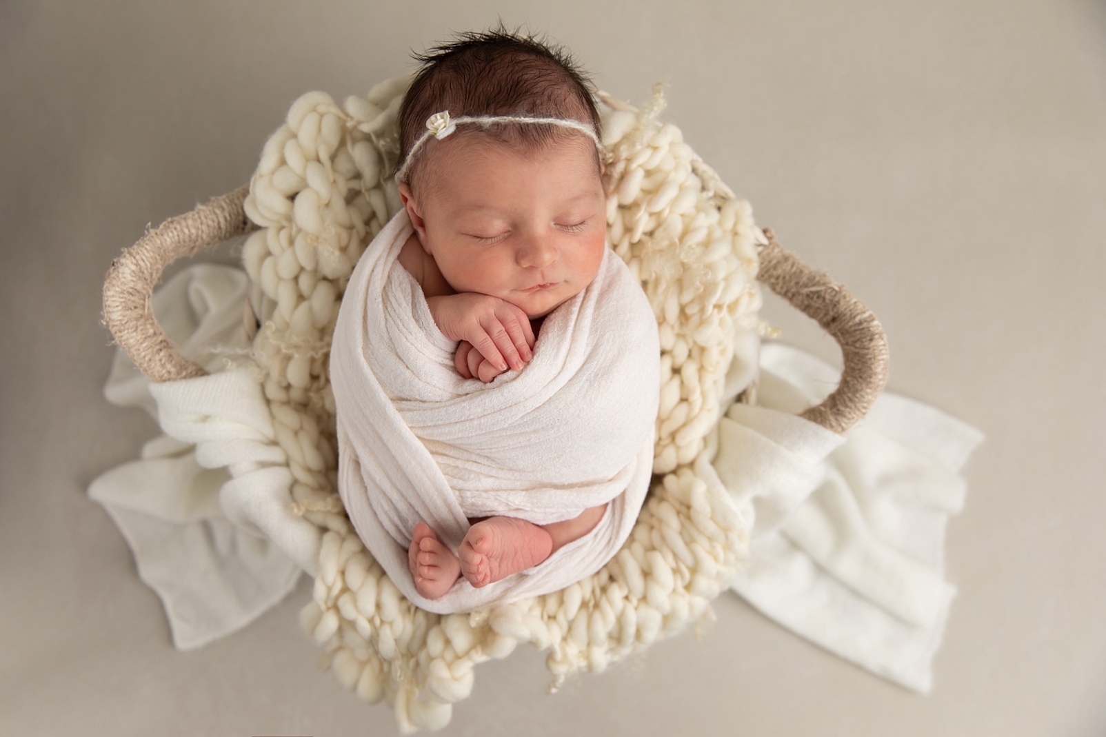 Newborn girl swaddled in a basket
