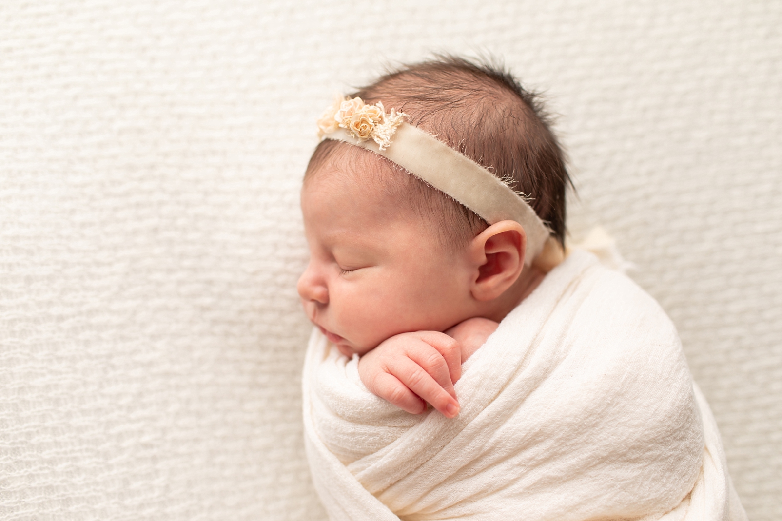 Newborn girl swaddled with decorative headband