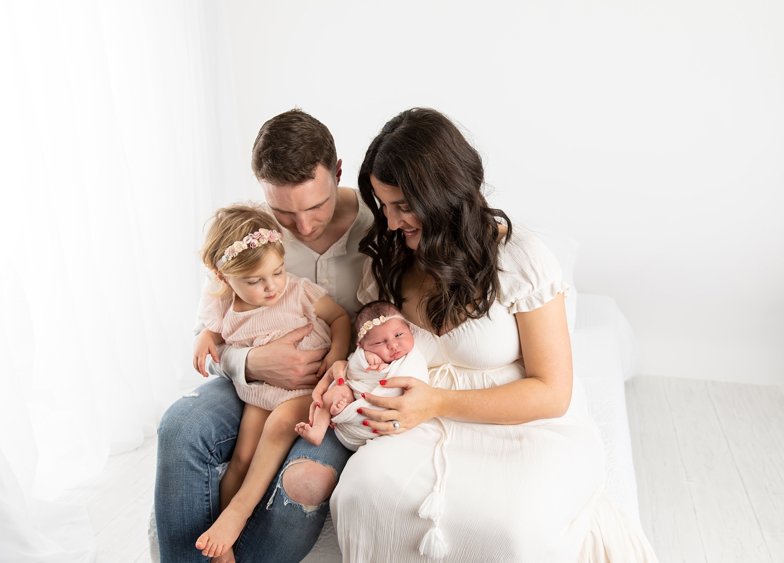 Family looking at their newborn baby with white curtains in the room | It's snuggle time
