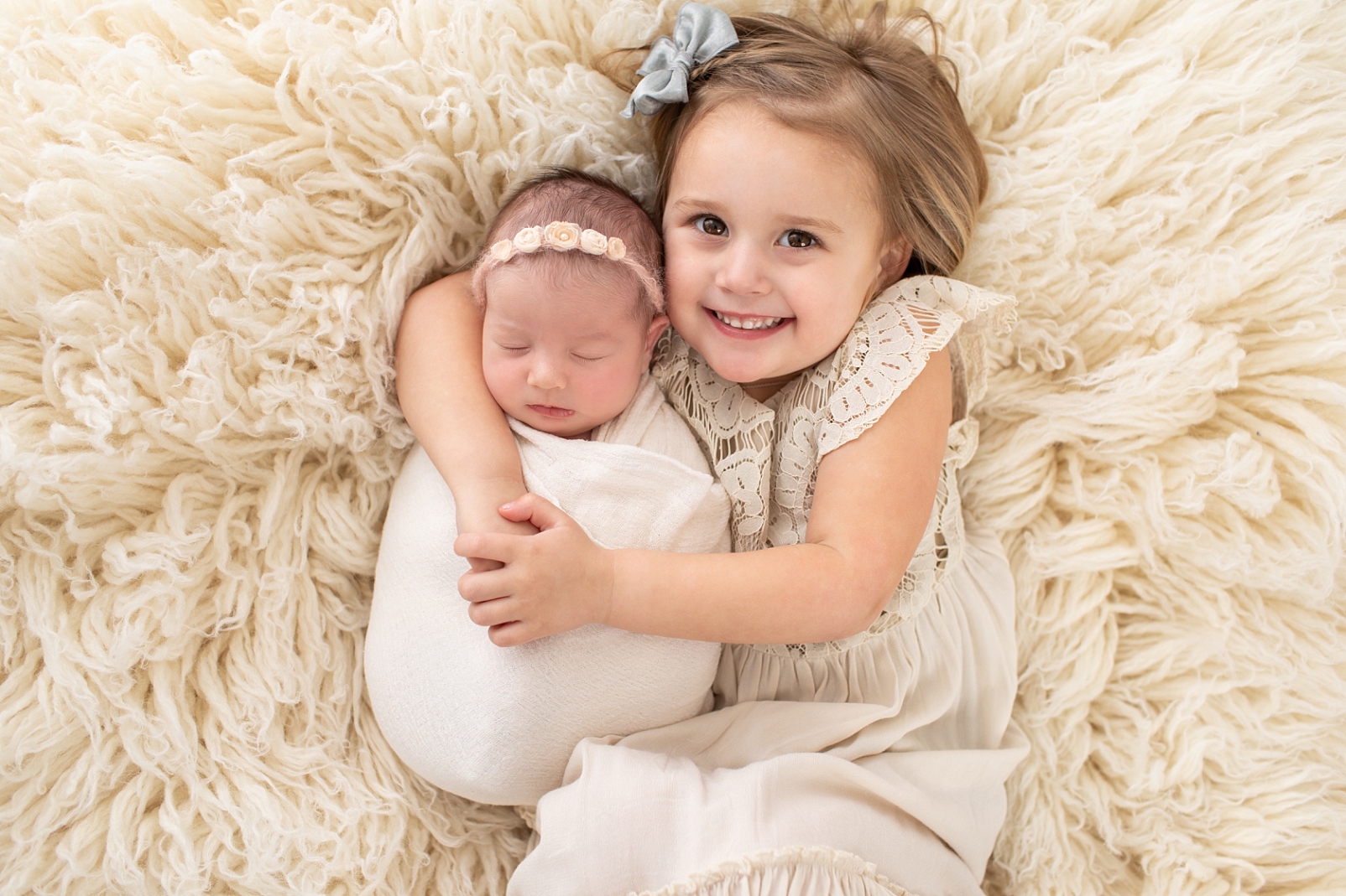 little girl hugging her newborn baby sister