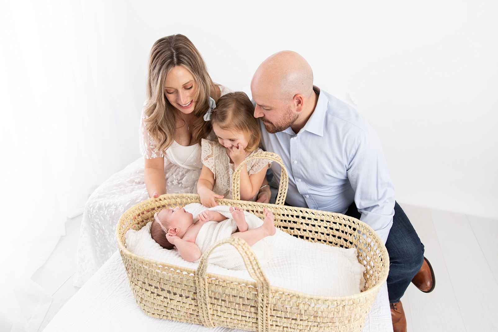 Ellicott City Newborn Photographer with a family looking at their baby in a Moses basket