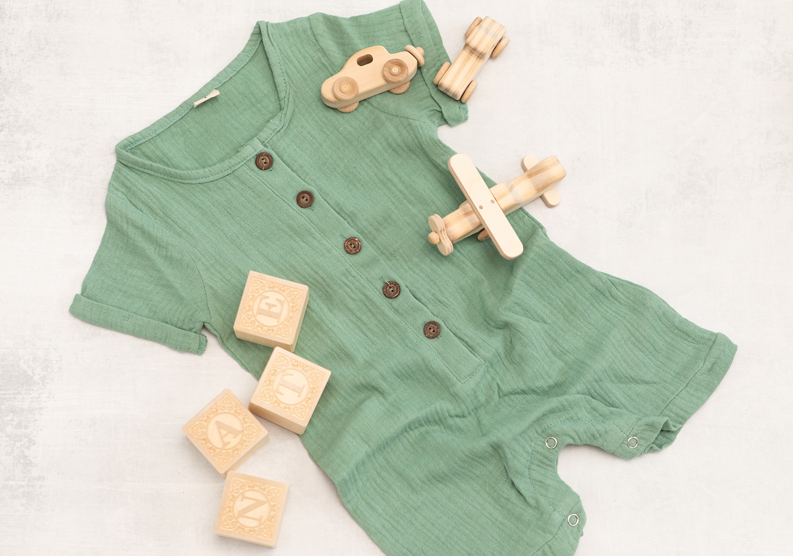 green boys button down romper with wooden blocks and cars 