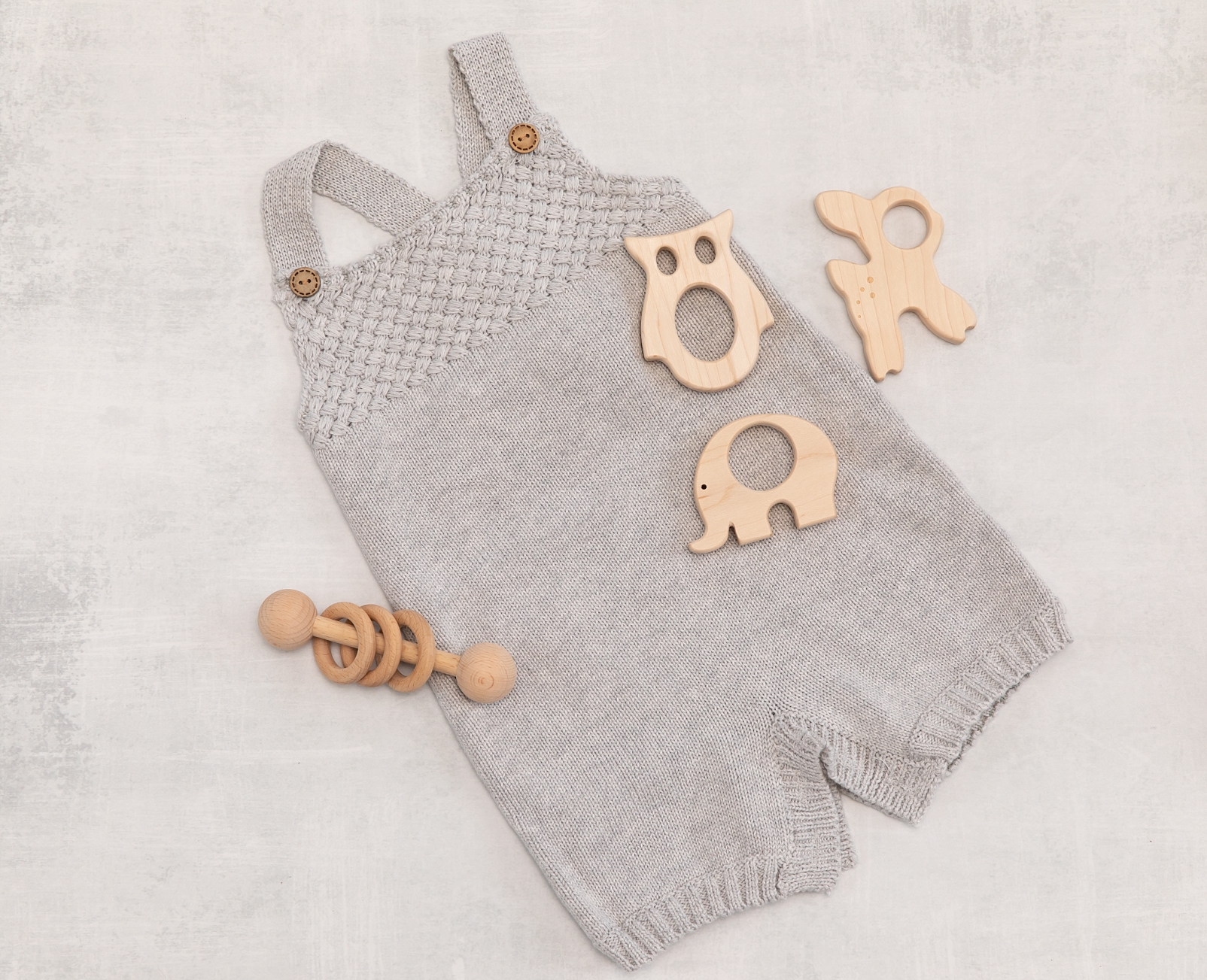 grey knit romper with wooden teethers and rattle 