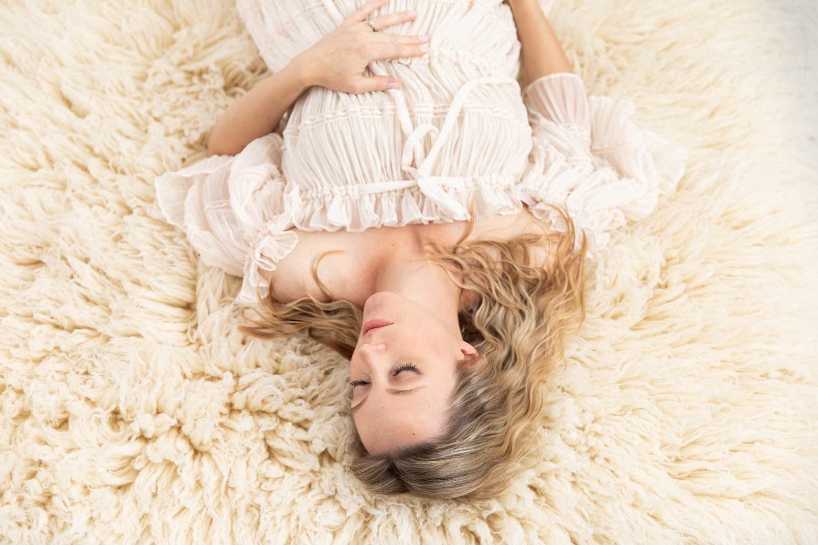 Pregnant mother lying on a flokati in a textured gown with 
Ellicott City Maternity Photographer | Rebecca Leigh Photography
