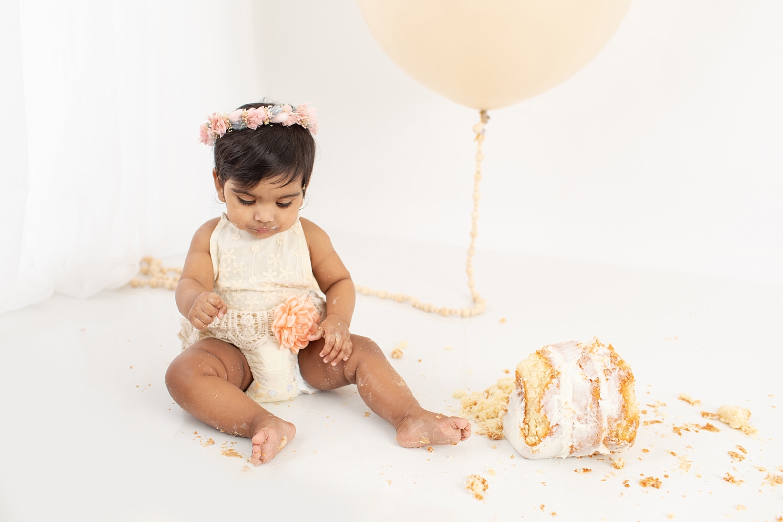 How to Choose a Smash Cake | 6" cake with textured white icing smashed on the floor and baby with decorative outfit and balloon eating cake
