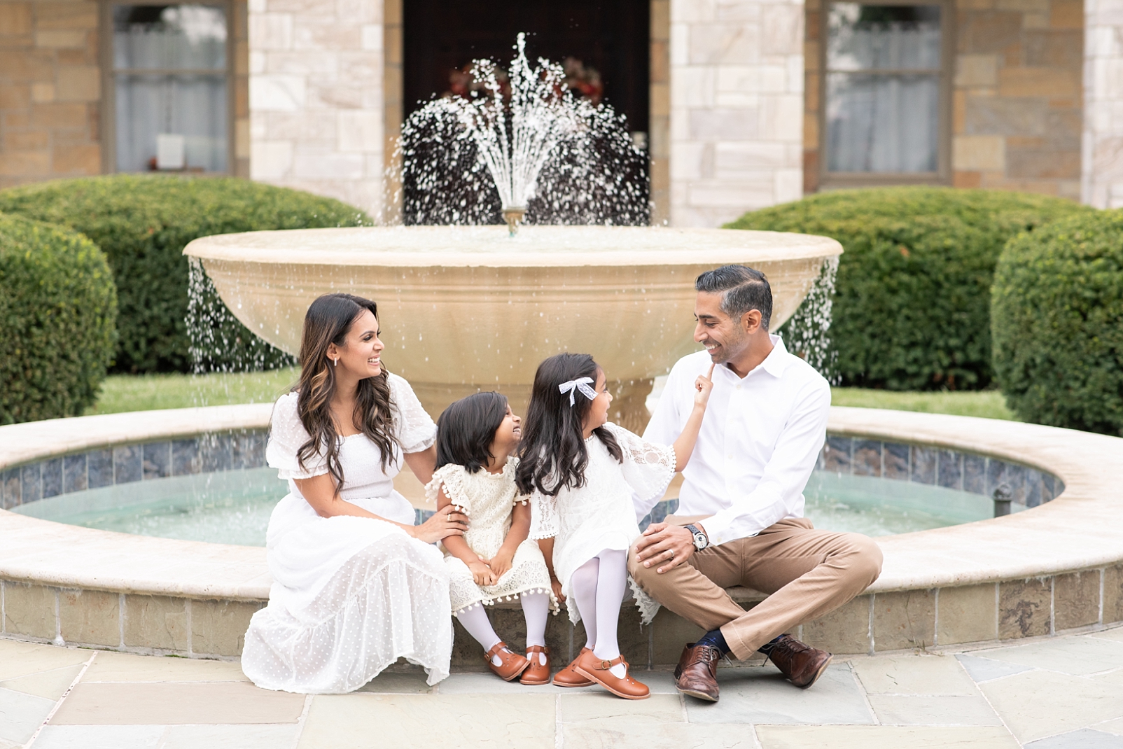 Family of 4 sitting in front of fountain