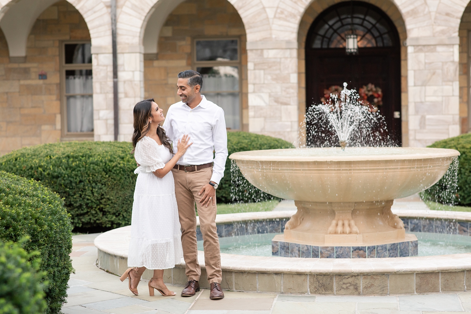 a wife and husband standing together in front of a fountain