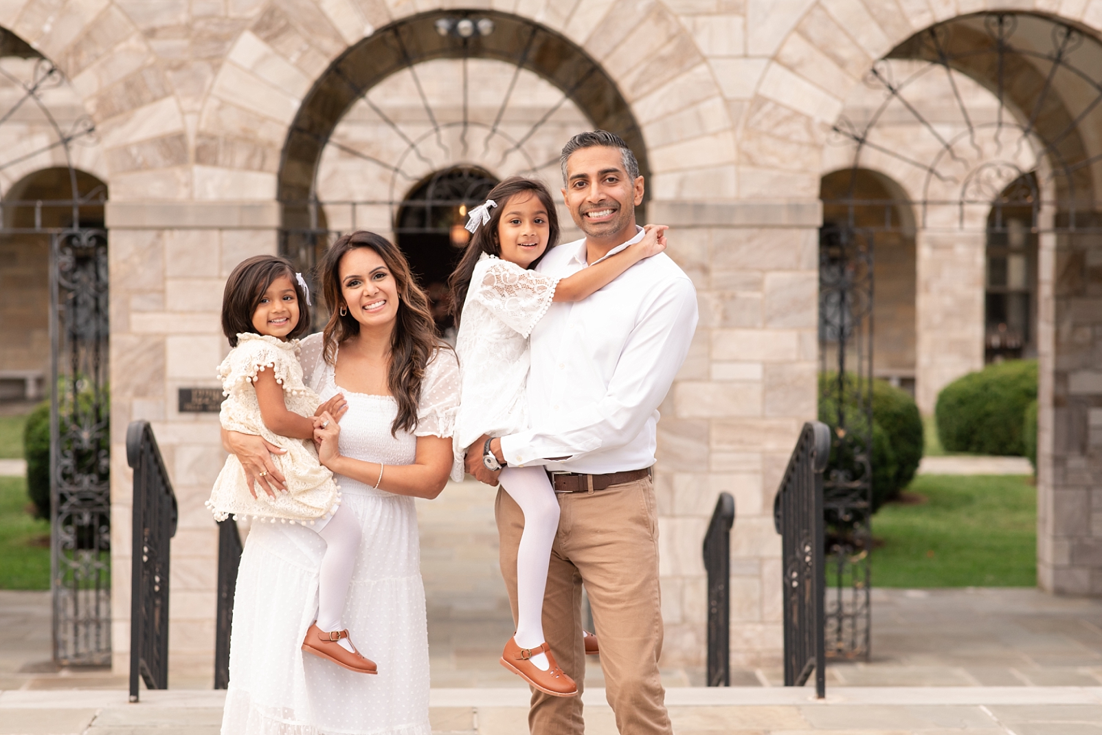 family of 4 wearing white dresses and standing in a white stone archway | How to achieve the best look for your outdoor portraits