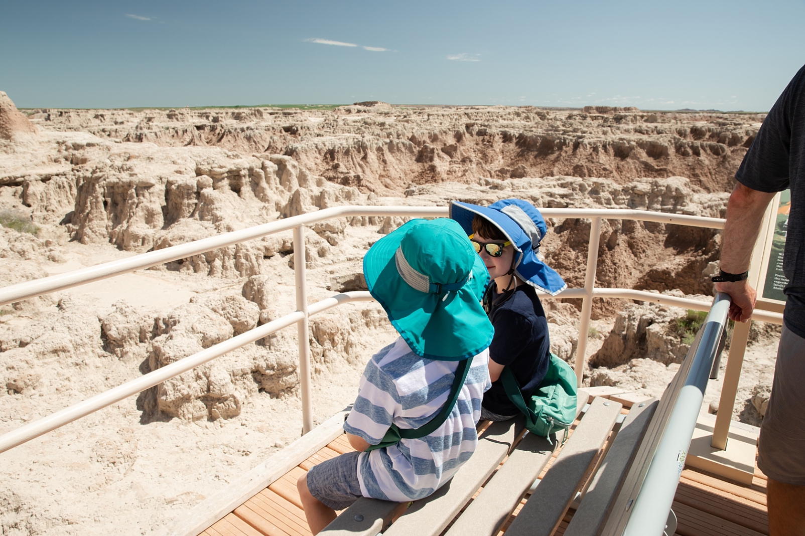 2 boys sitting on a bench wearing waist packs in the Badlands in South Dakota which is one of 10 travel tips with kids