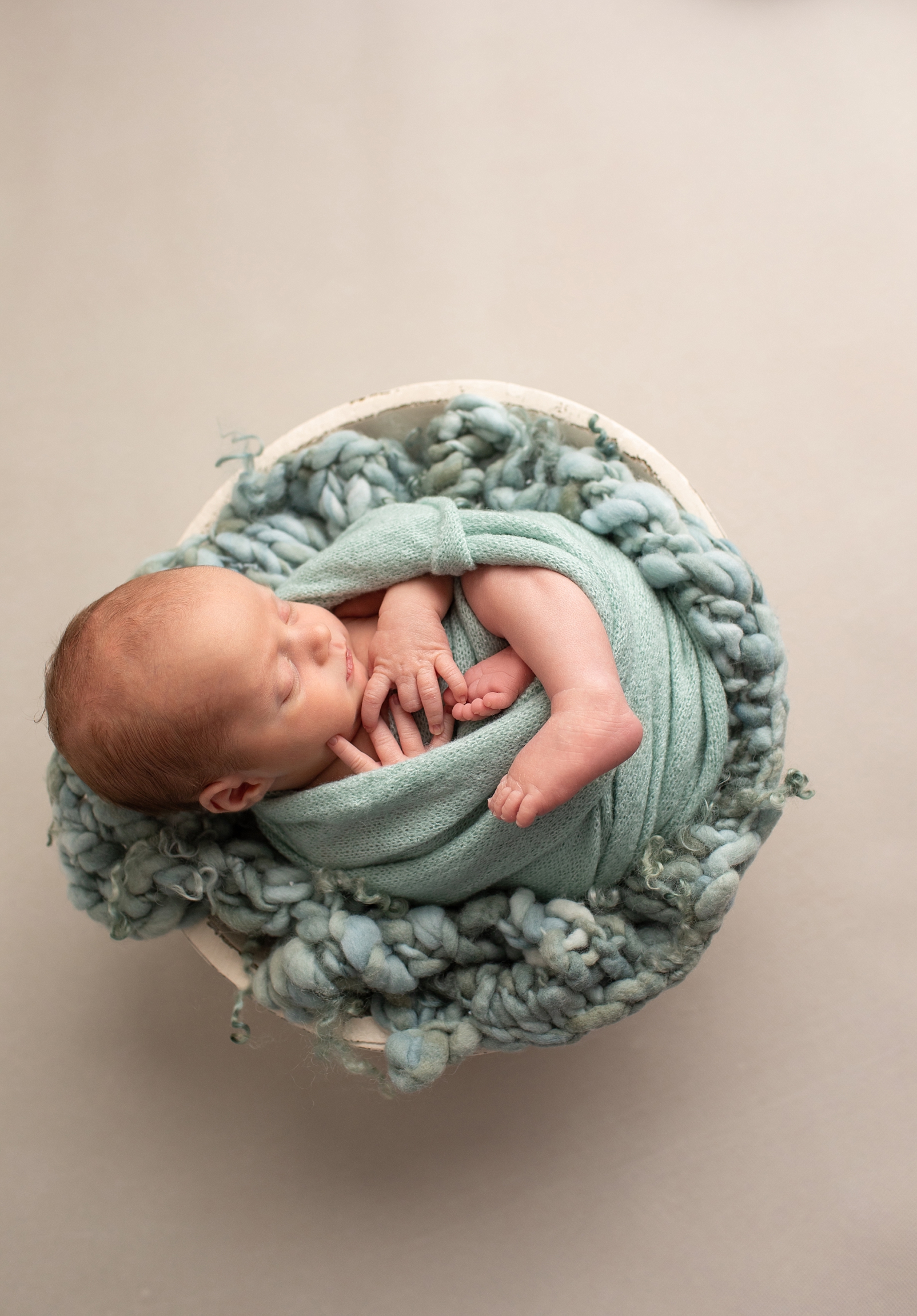 how to choose and download your digital images of a newborn boy wrapped in a blue green wrap in a bowl 