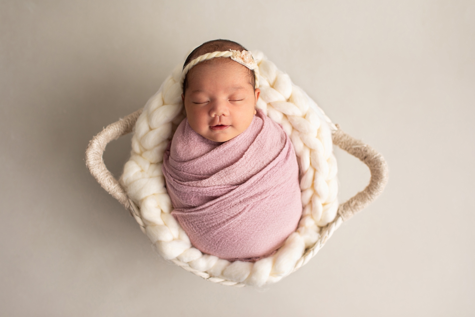 First Year Membership | Maryland Baby Photographer portraits of newborn girl wrapped in a mauve fabric in a basket with a chunky knit wool blanket 