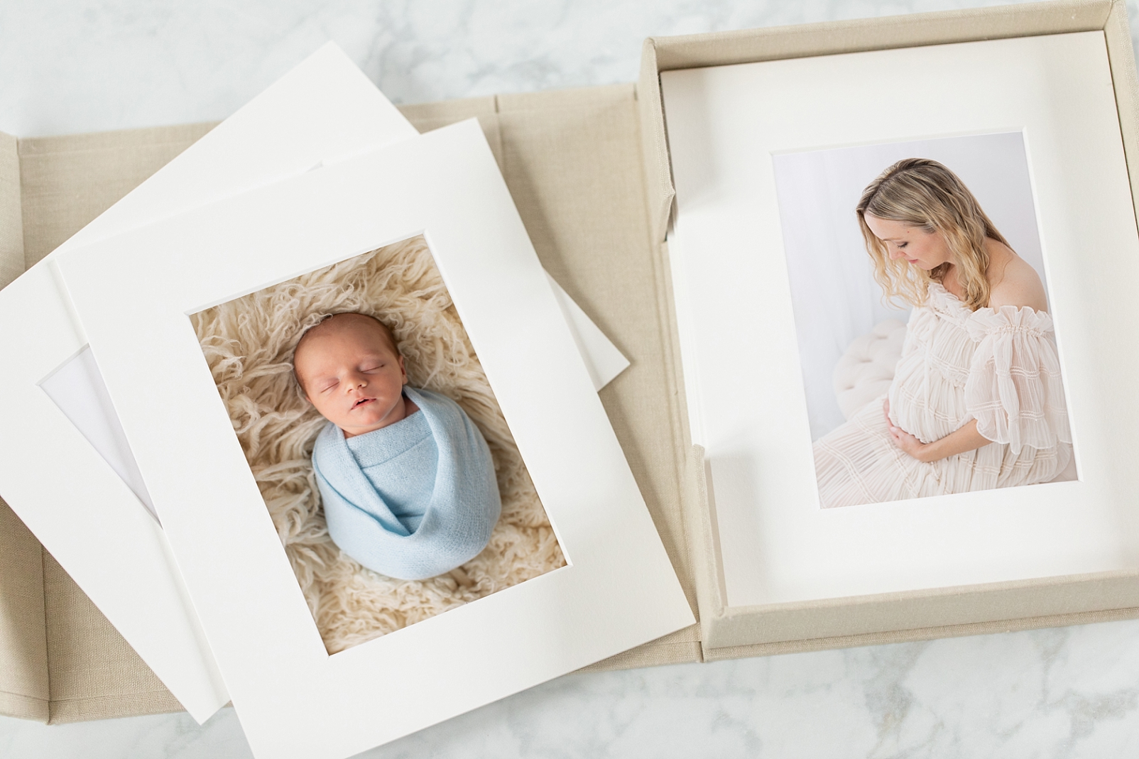 Newborn boy in light blue wrap on a flokati  featured in a white mat and a maternity photo of the mom displayed in a white mat
